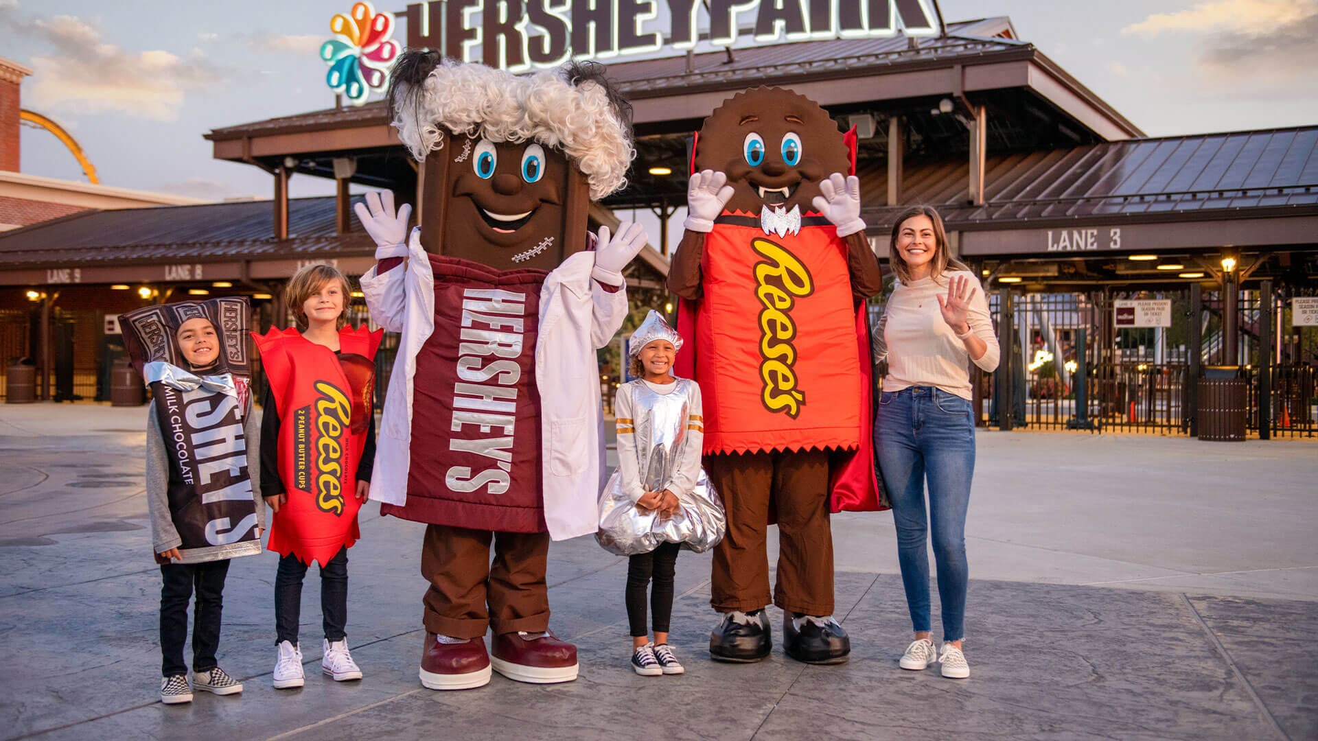 Family posing with Hershey candy characters outside the Hersheypark entrance during Halloween season