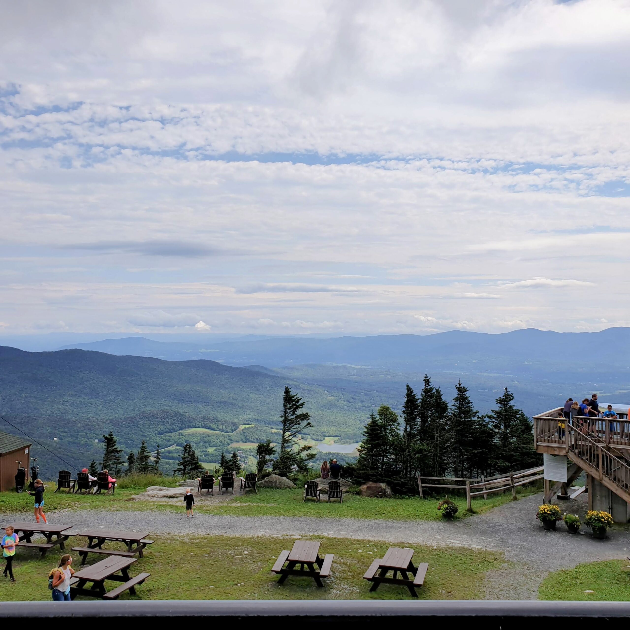 Panoramic mountain view from Stowe Mountain in Vermont with forested ridges and a broad cloudy sky