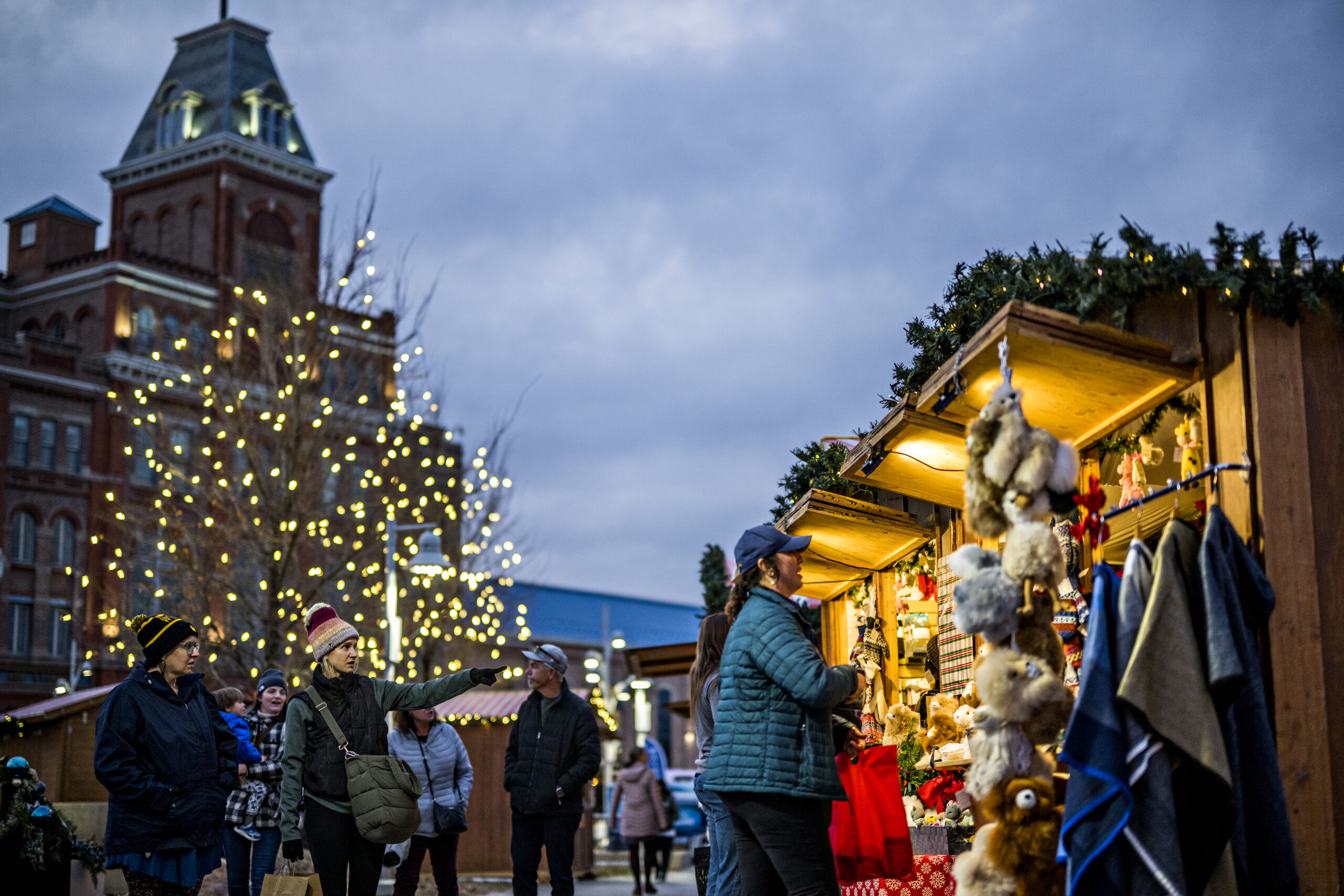 Visitors strolling through the Denver Christkindlmarket among illuminated holiday market stalls