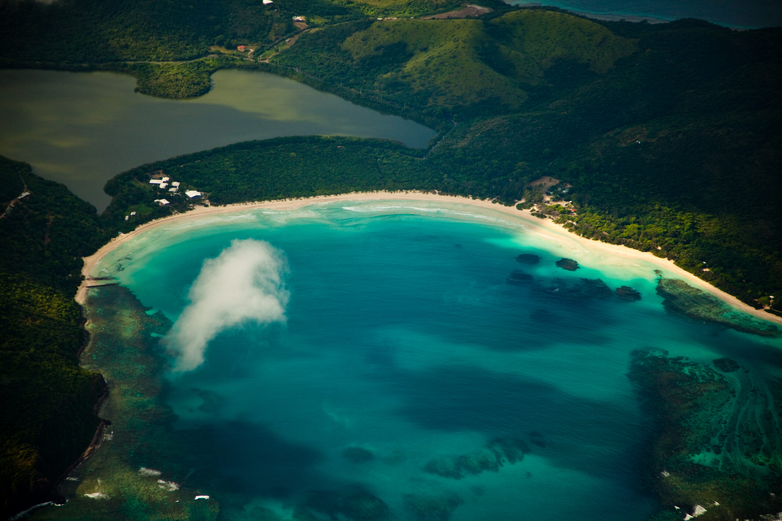 Aerial view of crescent-shaped Flamenco Beach on Culebra, Puerto Rico, surrounded by green hills and turquoise water