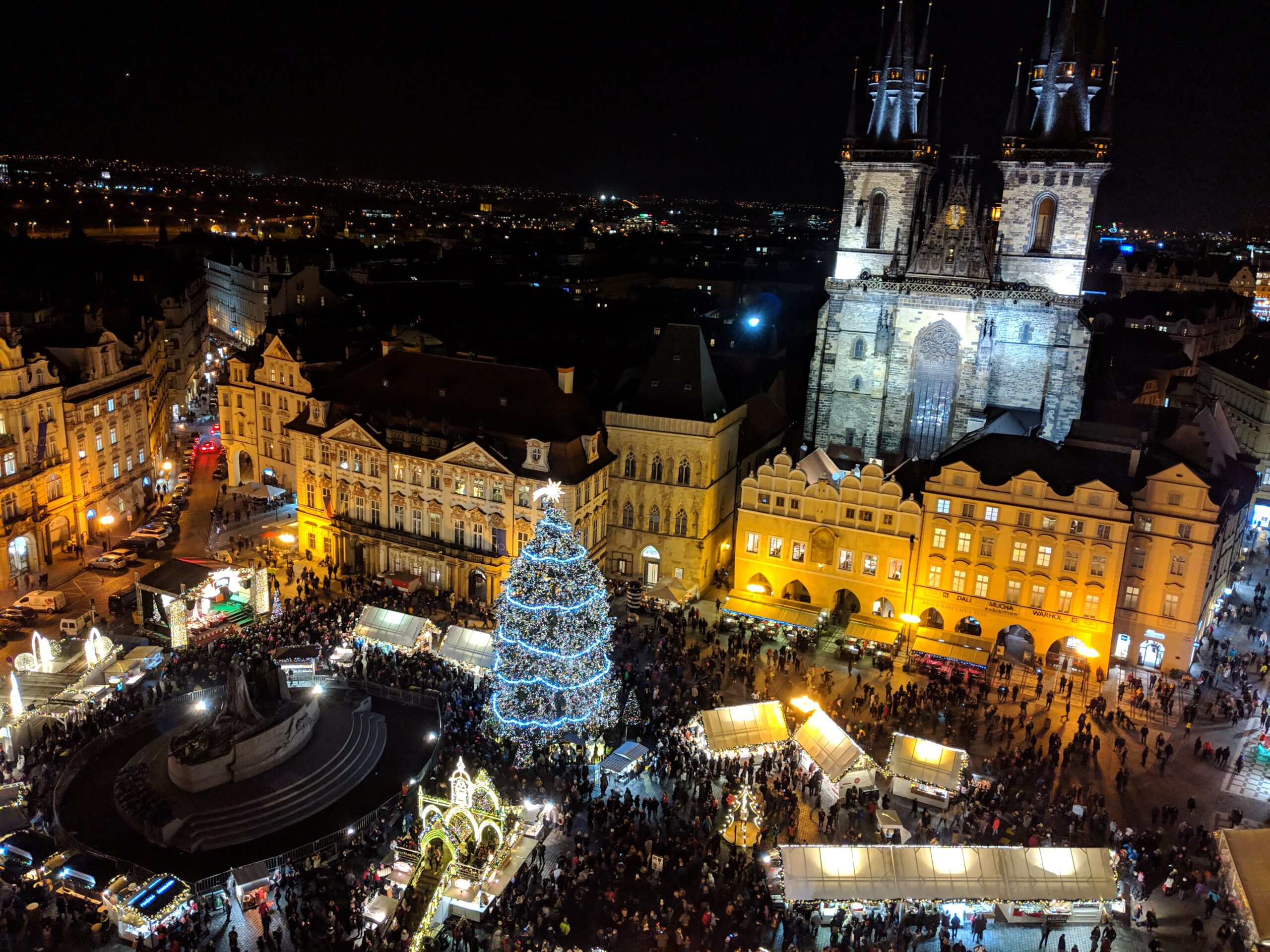 Prague Christmas market in Old Town Square at night with illuminated tree, market stalls and Church of Our Lady before Týn