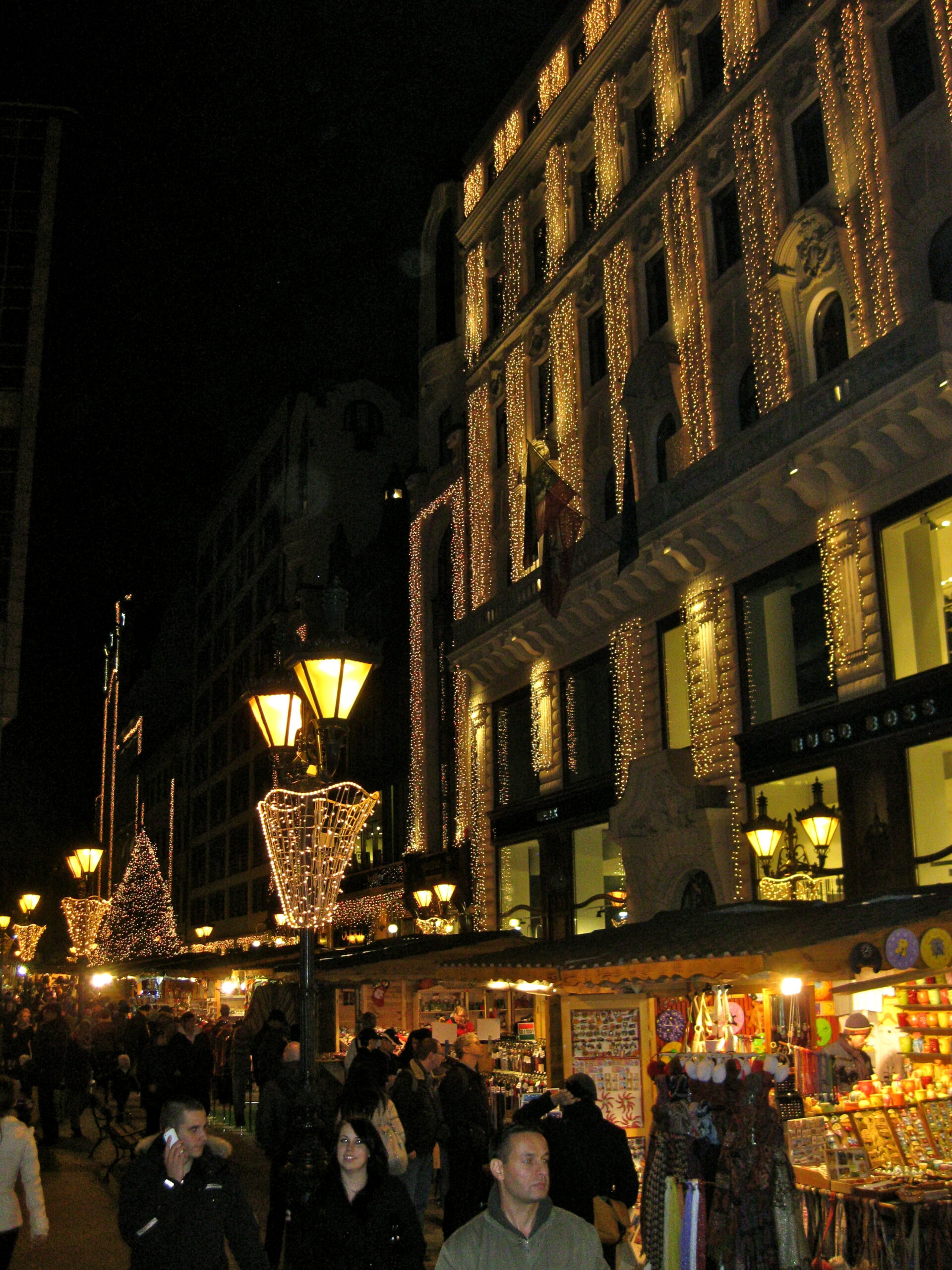 Budapest Christmas market stalls and illuminated buildings at Vörösmarty Square at night