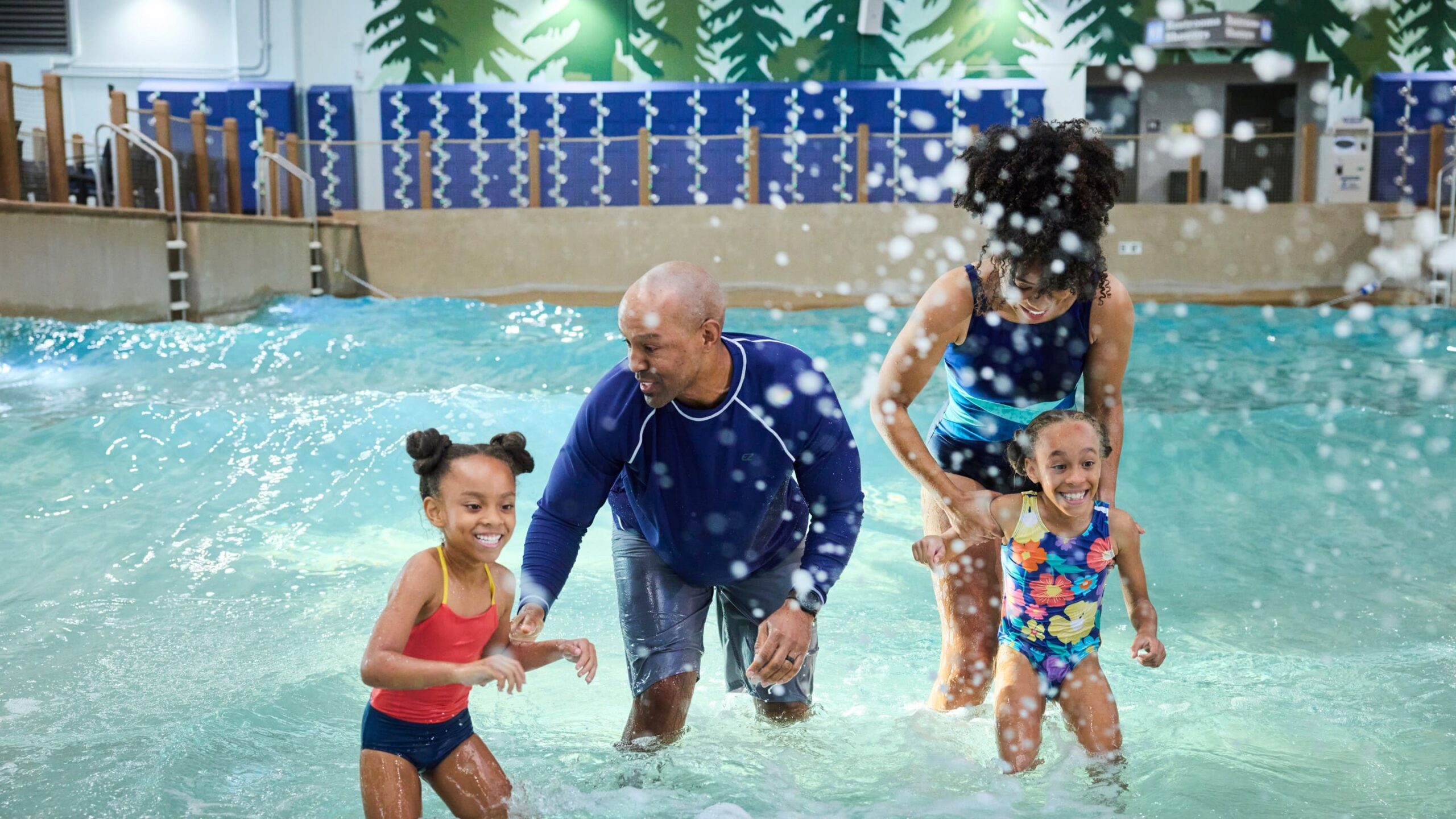 Family of four splashing together in the indoor wave pool at Great Wolf Lodge New England