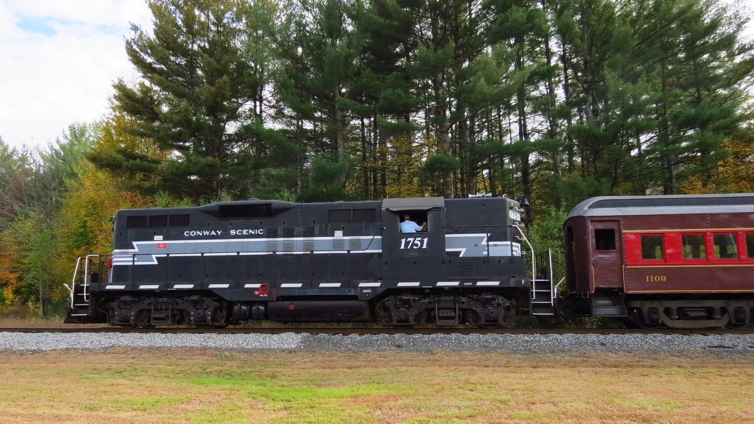 Conway Scenic Railroad locomotive and passenger cars traveling through autumn scenery near Bartlett, New Hampshire