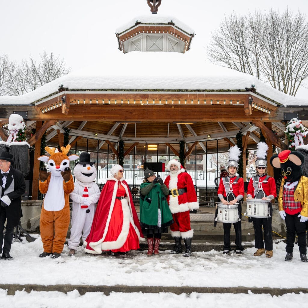 Santa, Mrs. Claus and holiday characters gathered at the snow-covered Leavenworth Christmastown gazebo