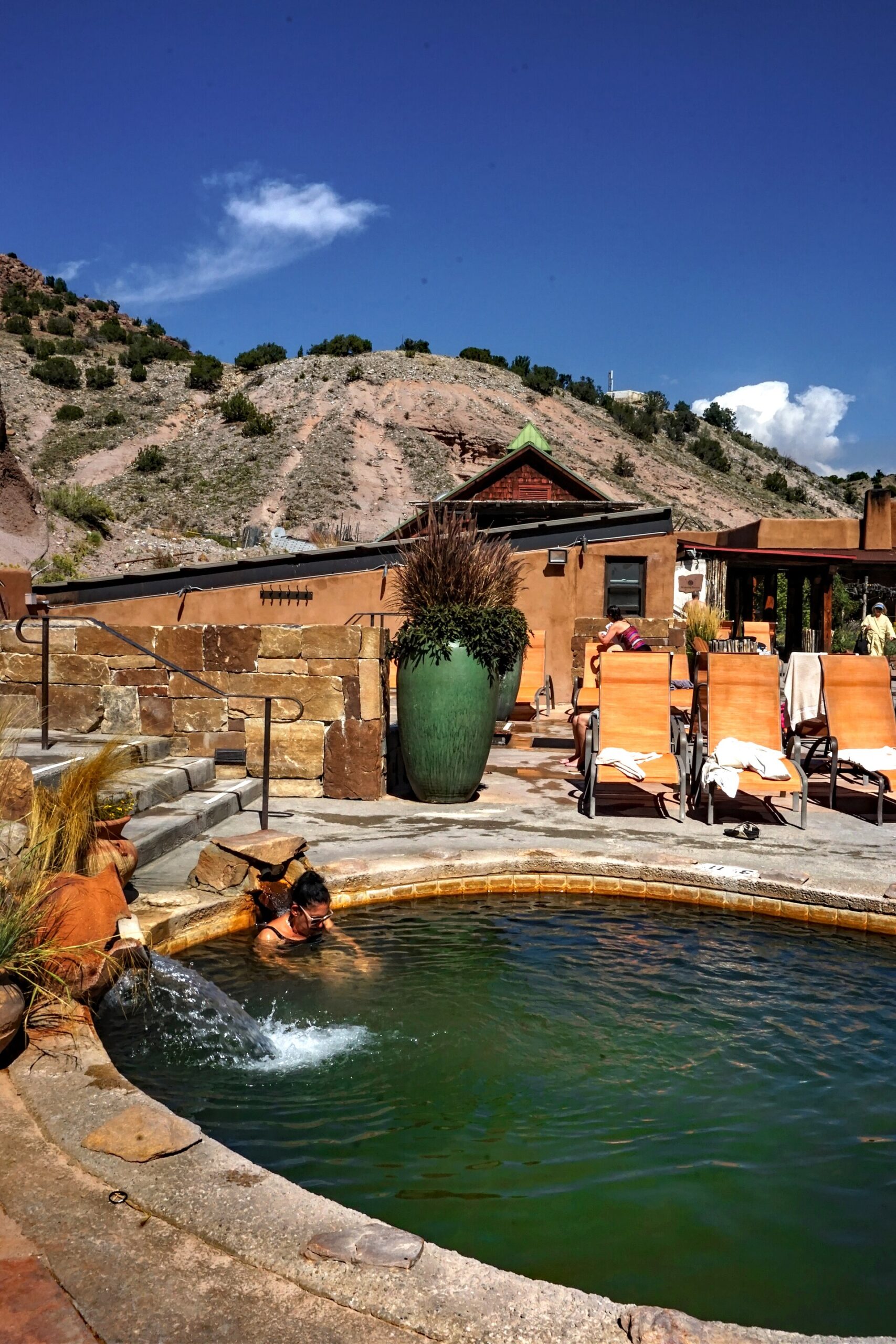 Mineral soaking pool at Ojo Caliente Mineral Springs Resort & Spa in New Mexico, with desert cliffs and resort buildings in the background