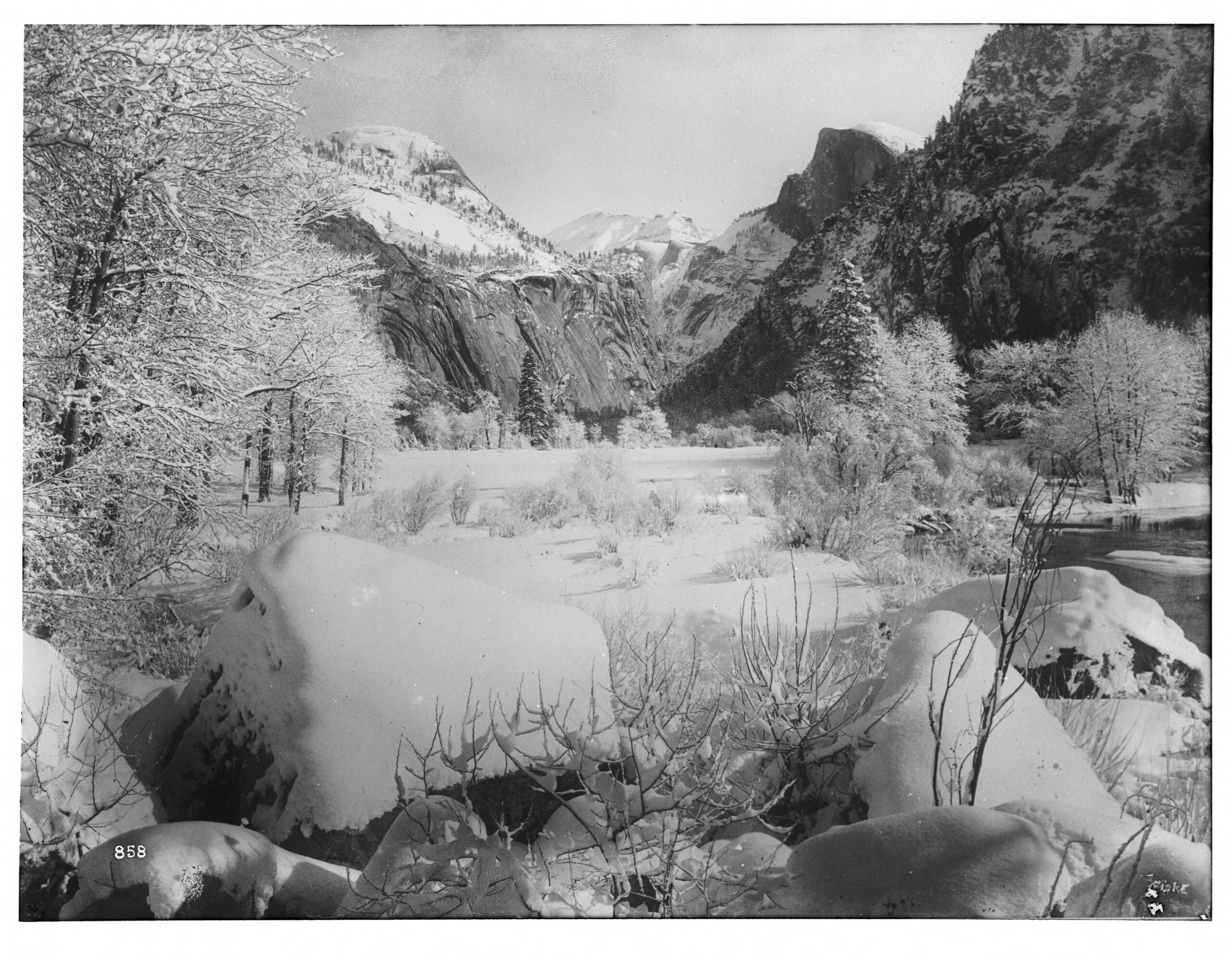 Snow-covered Yosemite Valley surrounded by steep granite cliffs and winter trees.
